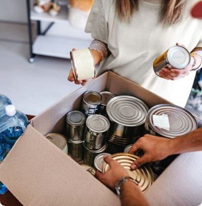 Careers that support community service are rewarding. This image is a closeup shot of someone putting canned food into a box.