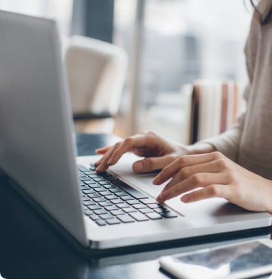 Woman taking her career to the next level by using Cardinal Financial technology. The image shows a closeup of her hands typing on a laptop.